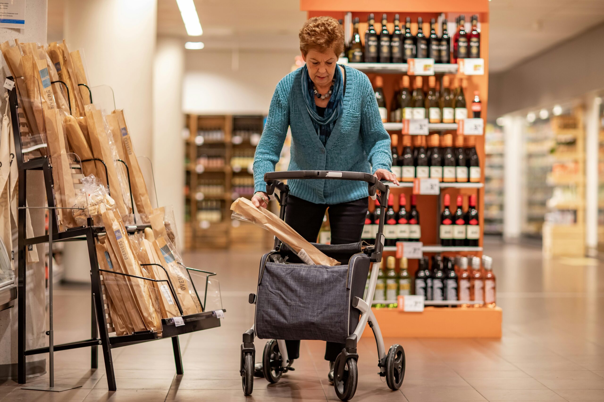 A service dog calmly sitting near shopping carts in a grocery aisle