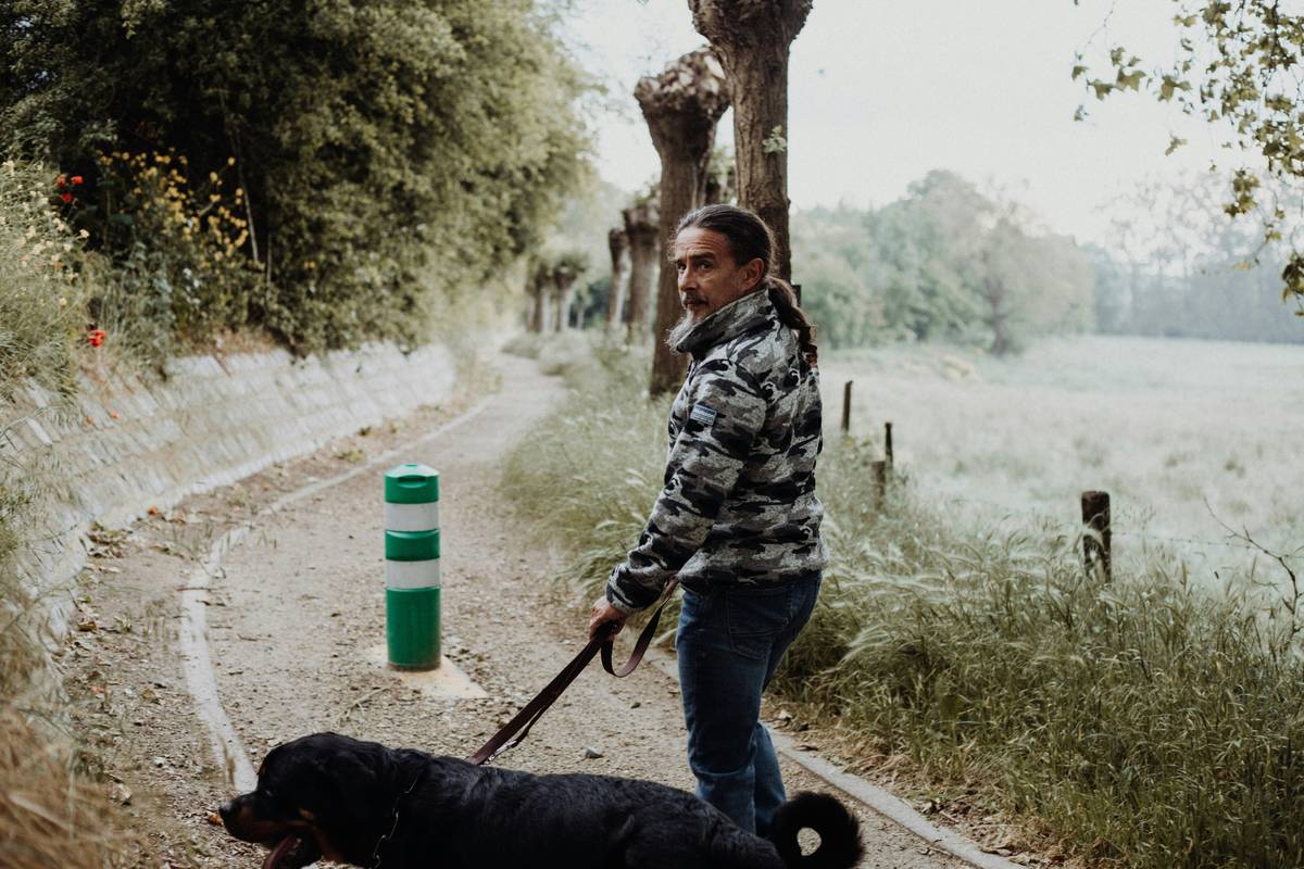 A trainer working with a service dog on leash control in a park.